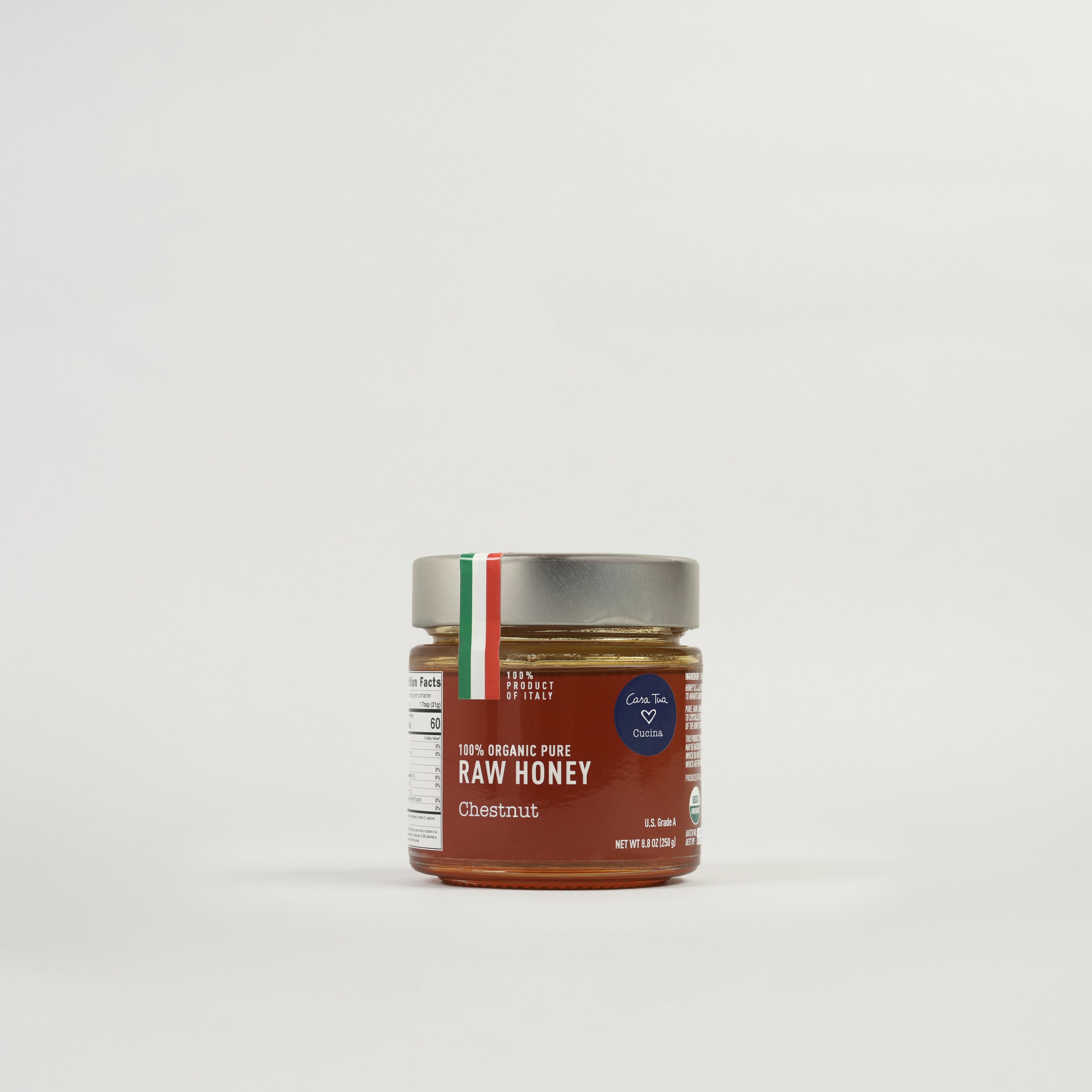 A jar of honey labeled '100% Organic Pure Raw Honey' with a red and white brand tag indicating it's a product of Italy.