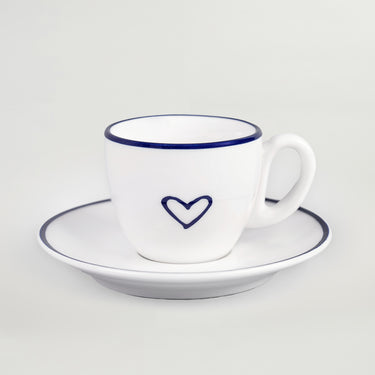 A white porcelain espresso cup with a blue heart design and matching saucer.