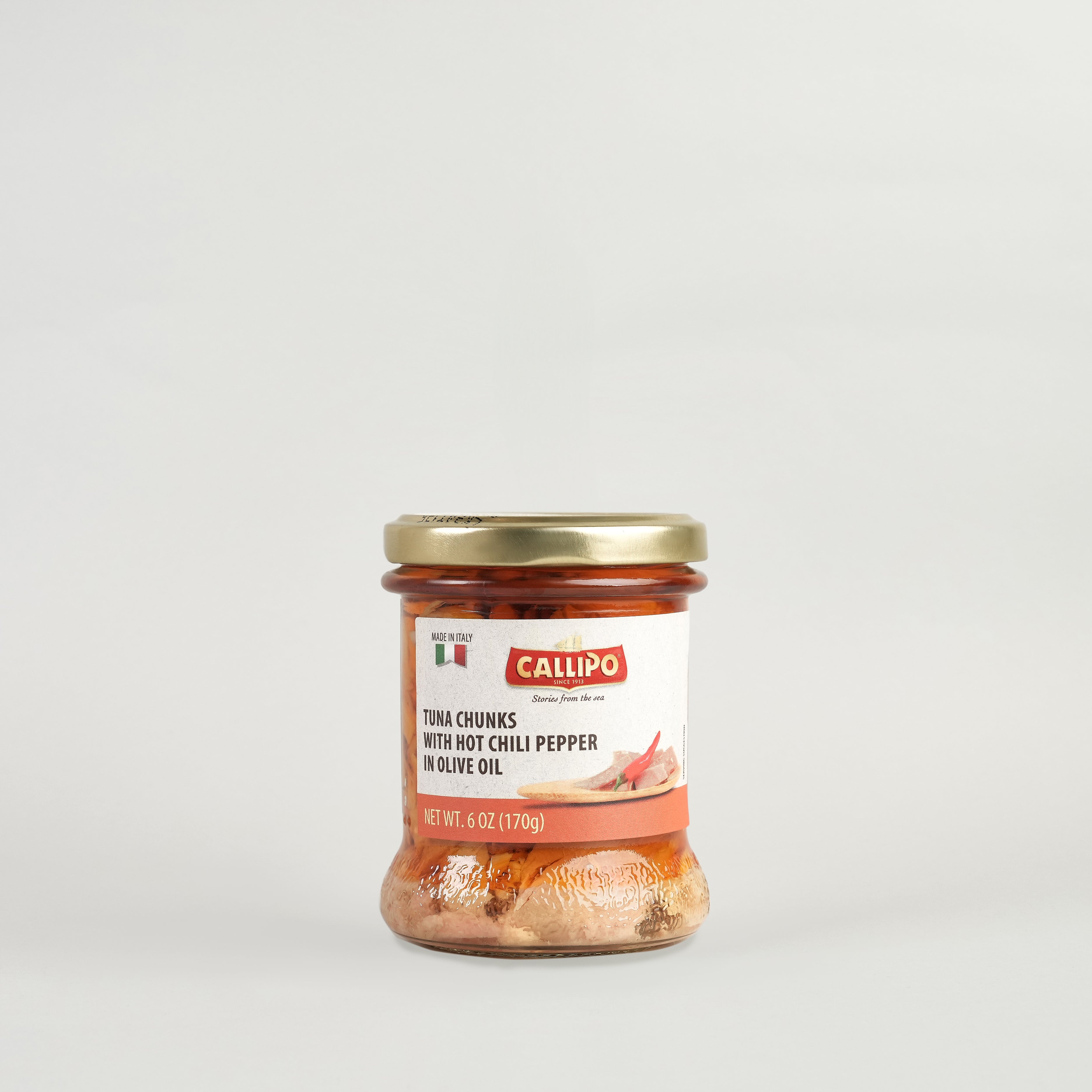 A glass jar containing Callipo tuna chunks with chili pepper in olive oil.