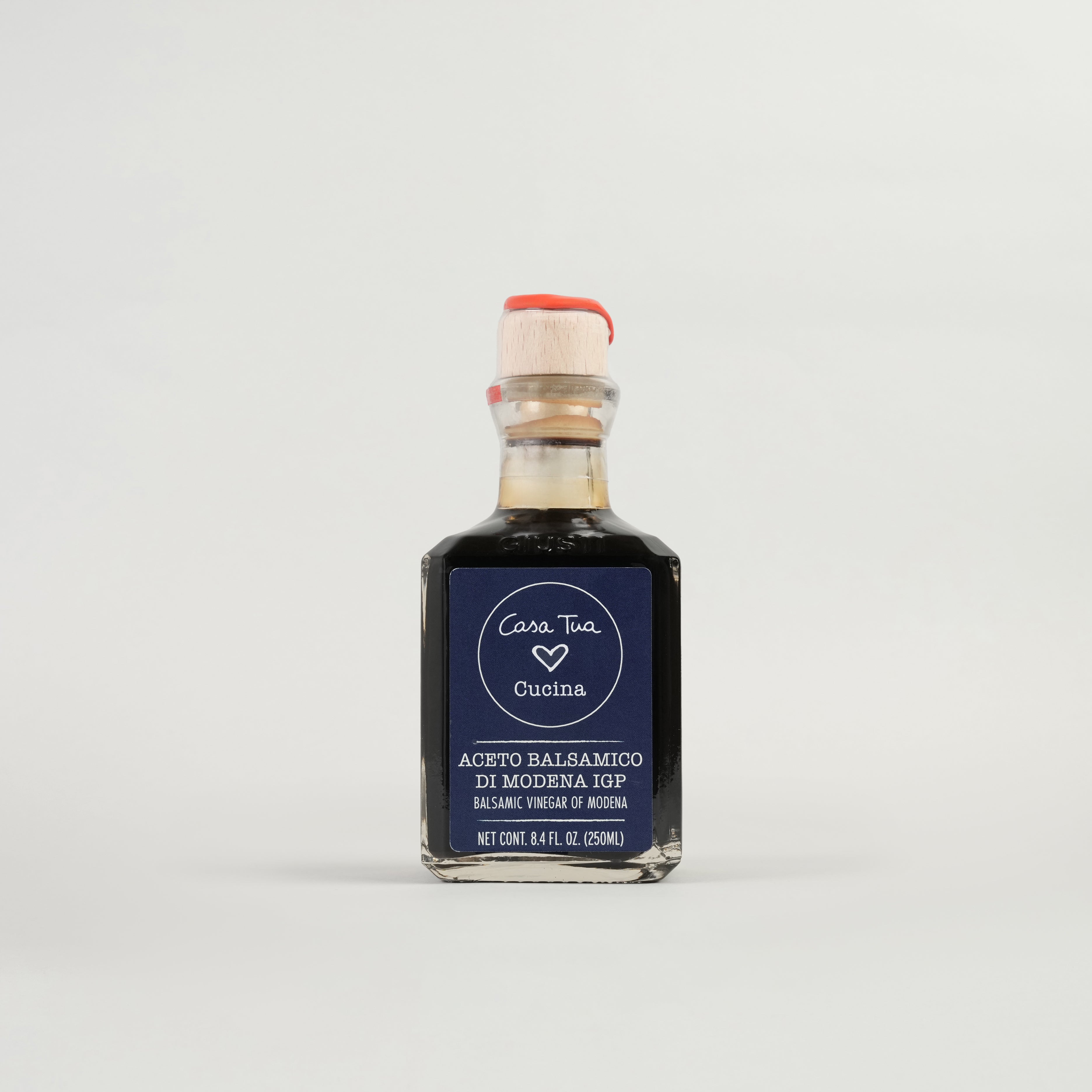 A bottle of Balsamic Vinegar of Modena with a label indicating it is an aged vinegar suitable for dressing salads, vegetables, and meats.