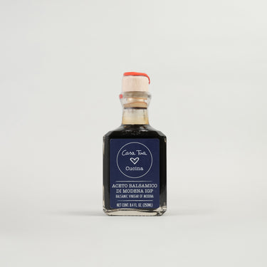 A bottle of Balsamic Vinegar of Modena with a label indicating it is an aged vinegar suitable for dressing salads, vegetables, and meats.