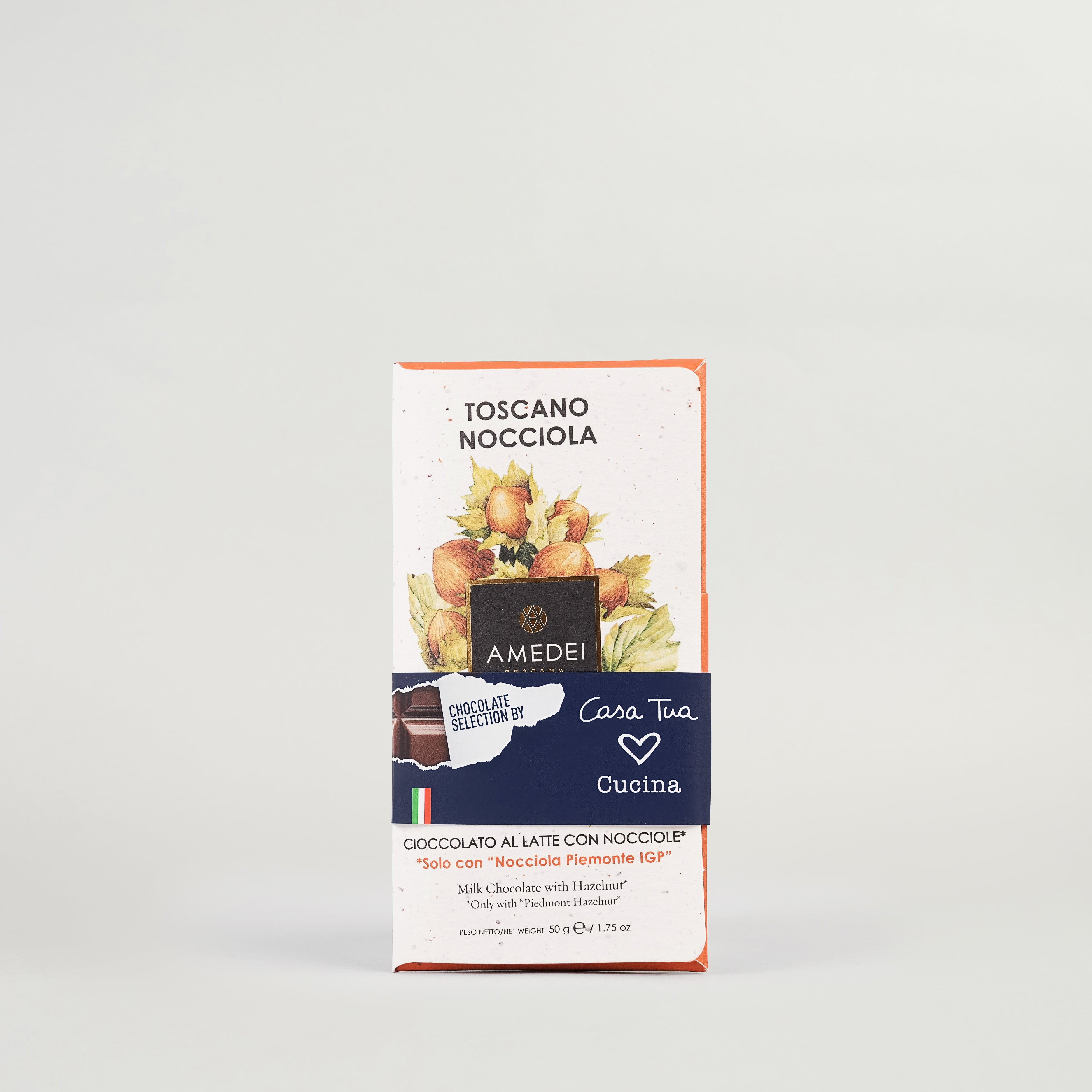 A packaged milk chocolate bar with hazelnuts, branded 'TOSCANO NOCCIOLA' by AMDEI, displayed against a white background.