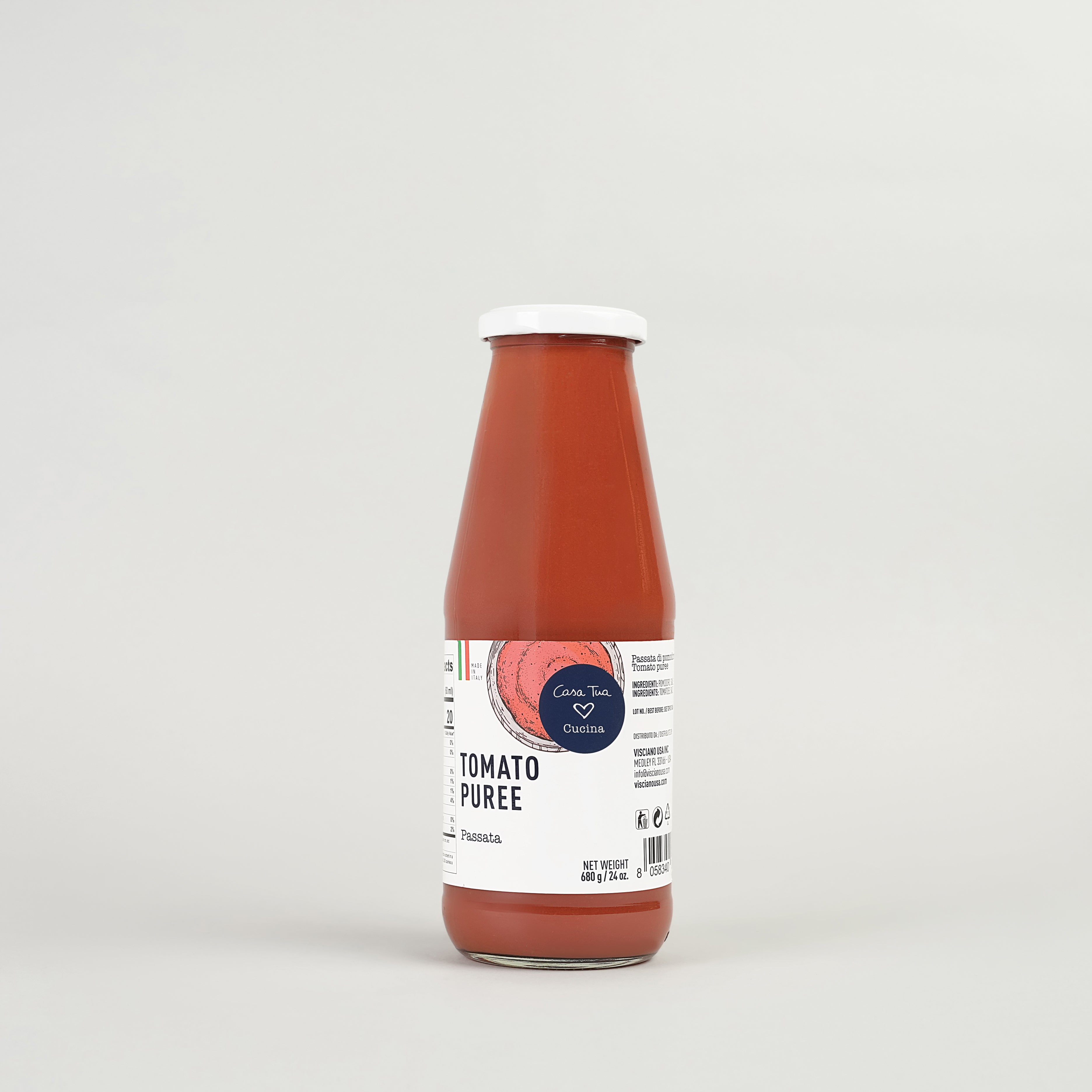 A bottle of tomato puree with a white cap and a label that includes the text 'Tomato Puree' and 'Passata'. The background is plain and the bottle is upright.
