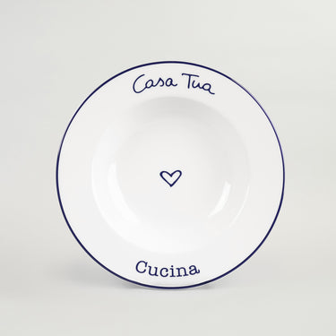 A white porcelain soup plate with blue rim and design, featuring the text 'Casa Tua' and 'Cucina' with a heart symbol in the center.