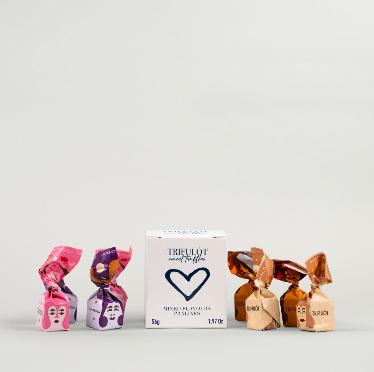 A selection of individually wrapped pralines in pink, purple, and brown colors, with a box labeled 'Trifulot' in the background.