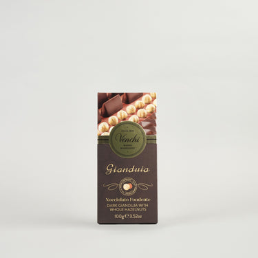 A packaged Venchi Milk Gianduja Bar, showing the bar and whole hazelnuts, with branding and product information on the label.