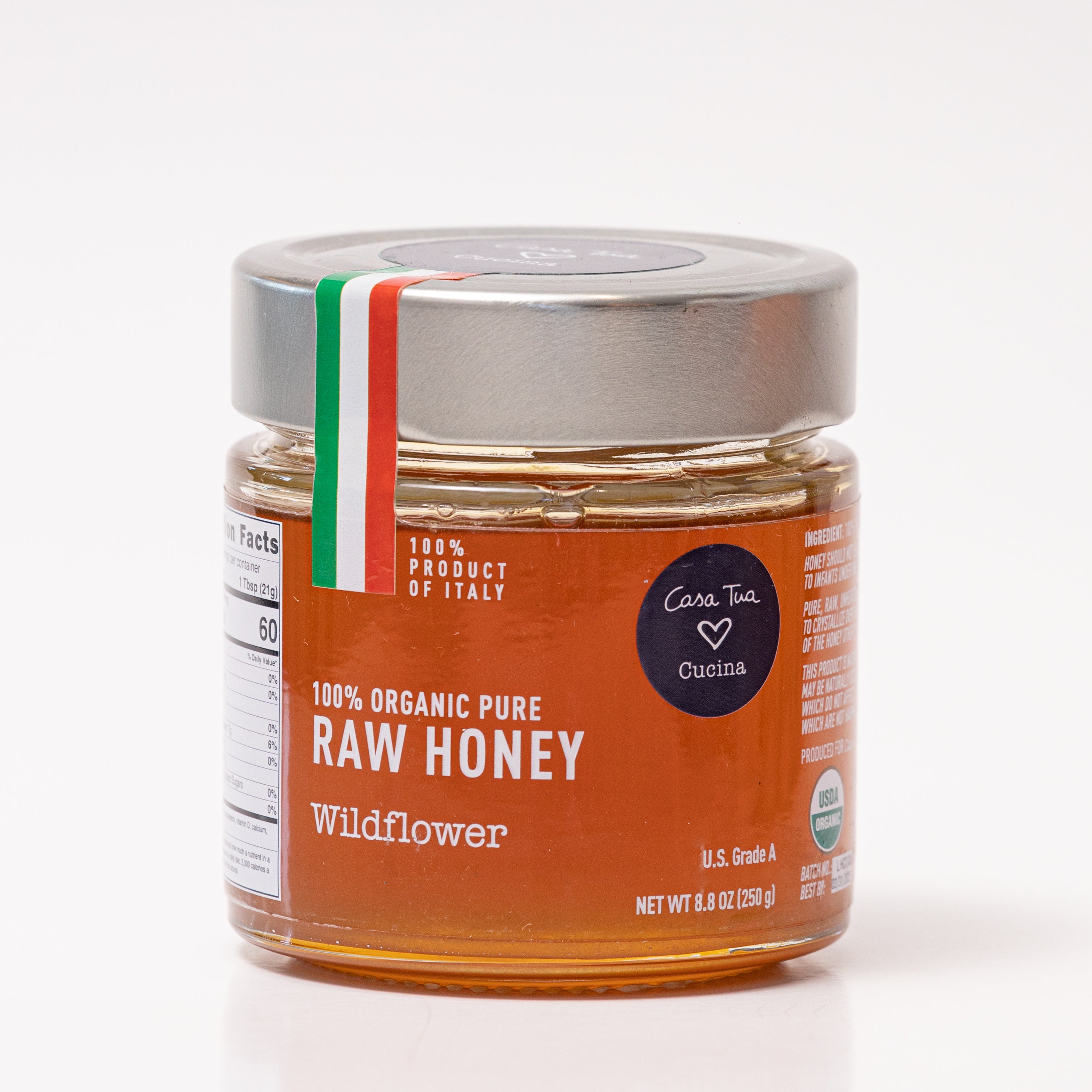 A jar of honey labeled '100% Organic Pure Raw Honey' with a red and white brand tag indicating it's a product of Italy.